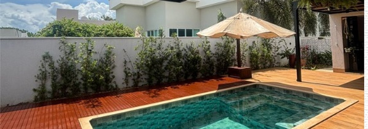 Deck de madeira contornando piscina com pergolado